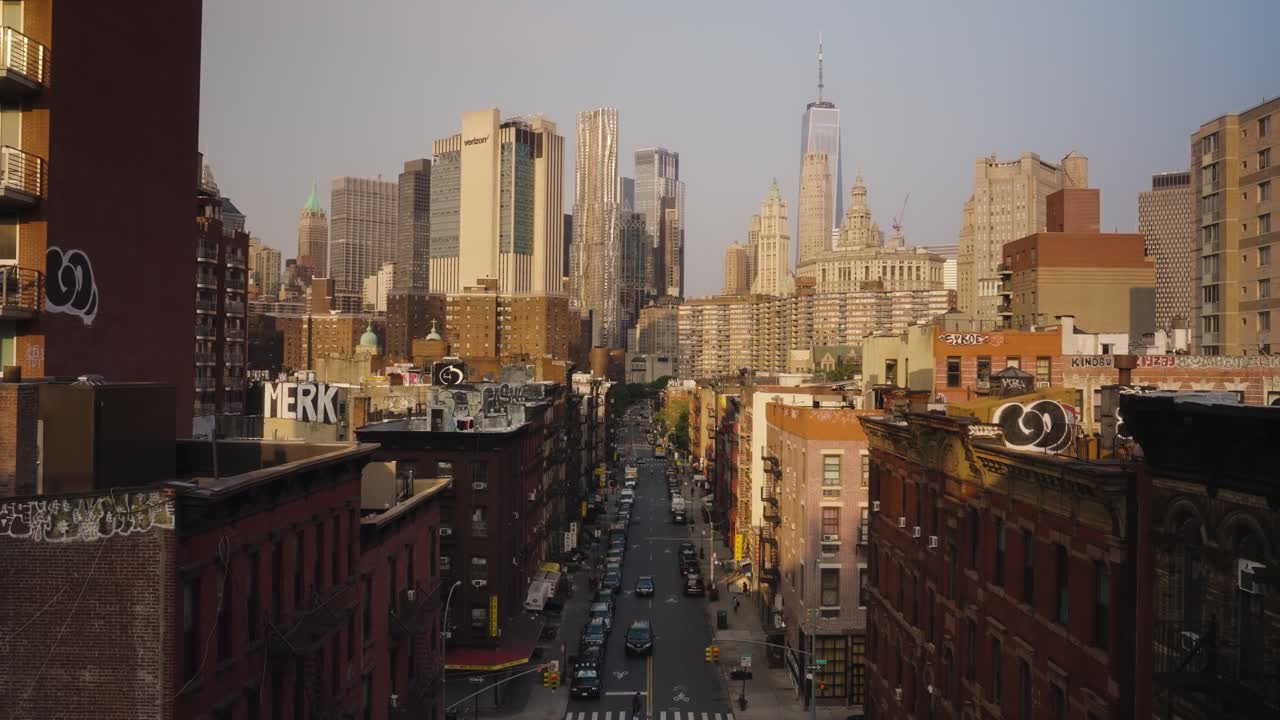 Slow backwards dolly showing busy road and skyline of New York City during golden sunset - Panorama view - Movement through hole in fence