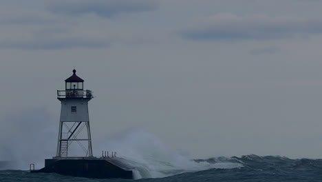 seagulls flying by lighthouse during storm on lake superior in grand marais, minnesota