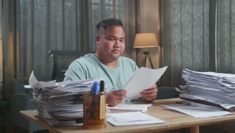 fat asian man smiling to camera while working with documents at the office