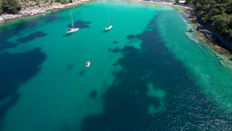 Drone-View-Slowly-Revealing-Aliki-Beach-With-Turquoise-Water-And-Mountains-Covered-By-Lush-Vegetation-In-The-Background,-Thassos,-Greece