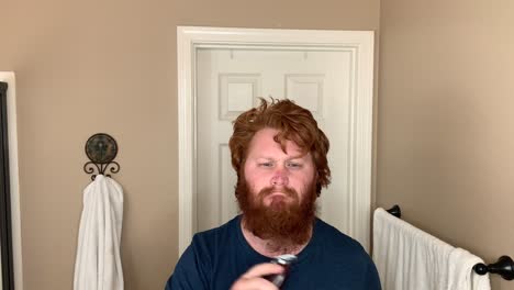 one single man shaving his own beard, still medium shot