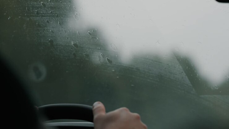Rainy drive view through wet windshield on highway
