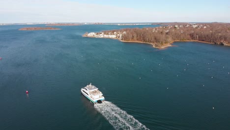 Static-drone-view-angled-down-of-an-underway-commuter-water-ferry-boat-on-a-sunny-fall-day-on-the-coast