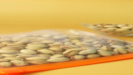 pistachios in a bag and bowl on a yellow background