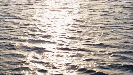 low flying bird's eye view of sunlight glistening across open ocean at golden hour