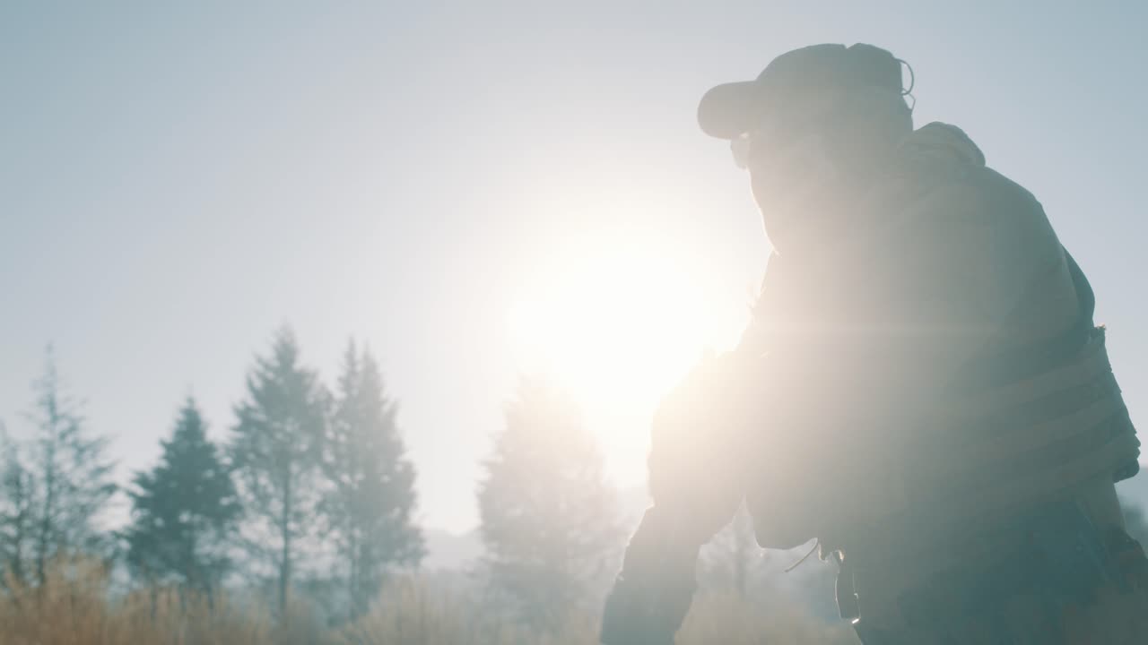 солдат стреляет из винтовки и пистолета на восходе солнца