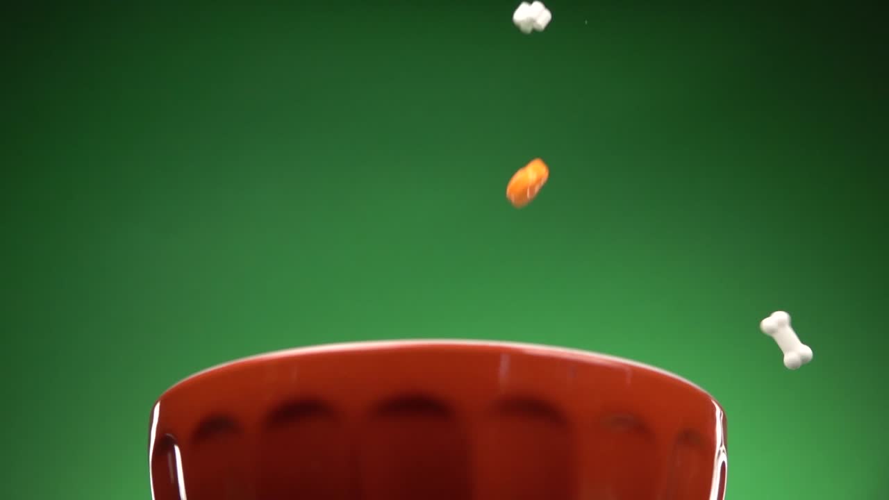 크로마 배경의 접시에 떨어지는 두개골과 뼈 모양의 사탕