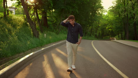 Closeup-young-man-walking-in-park-at-sunset.-Relaxed-model-guy-looking-at-camera