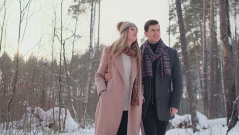 Joven-Matrimonio-Enamorado-Caminando-En-El-Bosque-De-Invierno.-Un-Hombre-Y-Una-Mujer-Se-Miran-Riendo-Y-Sonriendo-A-Cámara-Lenta.-Historia-De-Amor-Del-Día-De-San-Valentín.