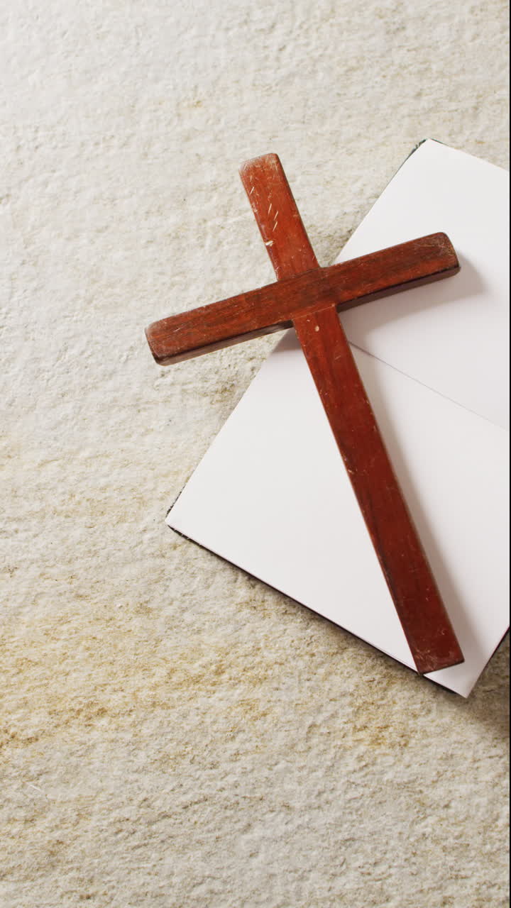 Vertical video of book and cross on white background with copy space