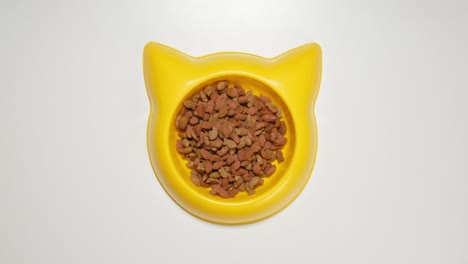 top view: cat meal fill a yellow dish (stop motion)