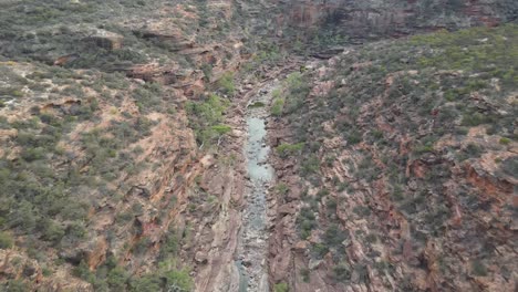 Drone-aerial-panning-down-over-an-Australian-gorge-and-national-park-with-a-river-flowing-on-a-sunny-day