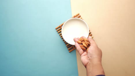 añadiendo almendras a un tazón de leche de almendra