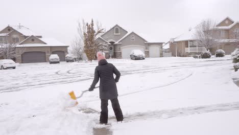 Woman-shoveling-snow-from-her-driveway-after-a-storm