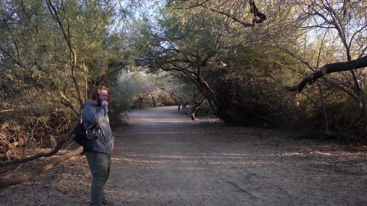 Red hair man walking vaping then cough in a park.