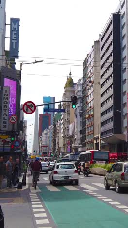 vertical cityscape of corrientes avenue, business center of buenos aires city, argentine downtown, traffic, theaters and people at daylight
