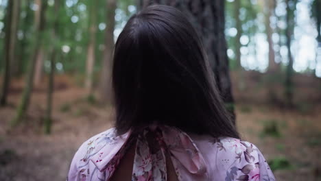young girl in front of huge old tree amidst dense forest. tilt-up