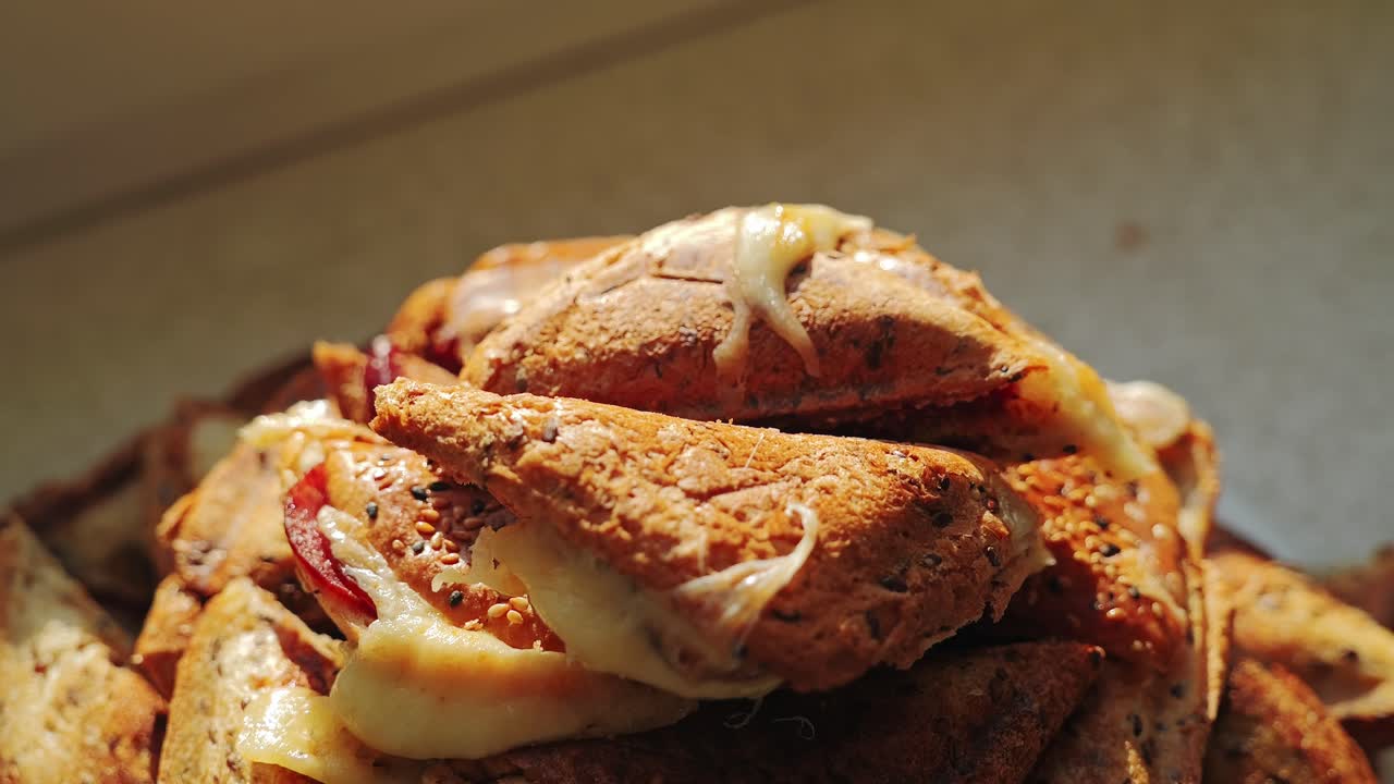 Slow motion close-up of female hands topping grilled sandwich stack with toast