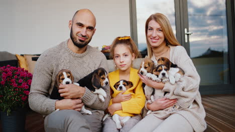 una familia con un niño y una mascota se sienta en la veranda de la casa de nieve. retrato de una familia feliz