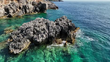 Toma-Aérea-De-Acantilados-Escarpados-En-La-Isla-De-Corfú-Con-El-Claro-Mar-Iónico