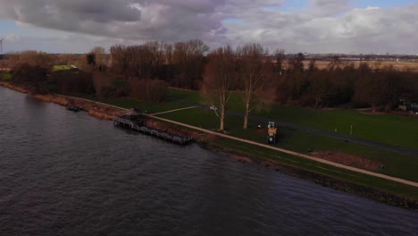 Vista-De-Arboristas-Preparándose-Para-Cortar-árboles-Junto-A-Oude-Maas-Sobre-Hierba-En-Barendrecht