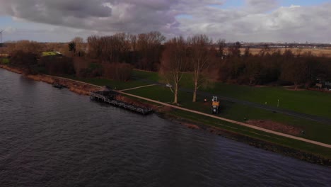 view of arborists getting ready to cut tree beside oude maas on grass in barendrecht