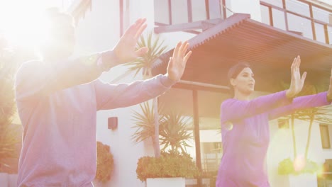 video of relaxed diverse couple exercising tai chi in garden