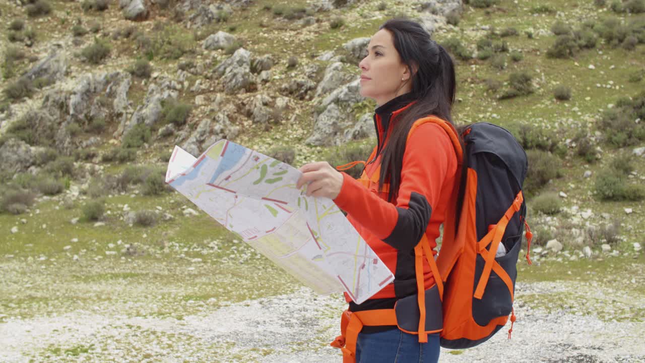 una mujer joven haciendo senderismo usando un mapa.
