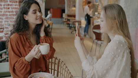 two women taking selfie in a cafe