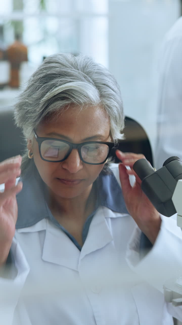 Scienziata anziana concentrata che si mette gli occhiali in laboratorio