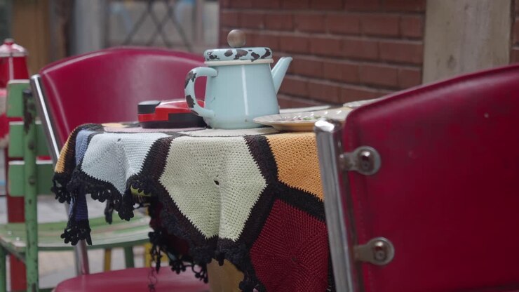Tavolino da caffè vintage all'aperto con tovaglia colorata lavorata a maglia e teiera