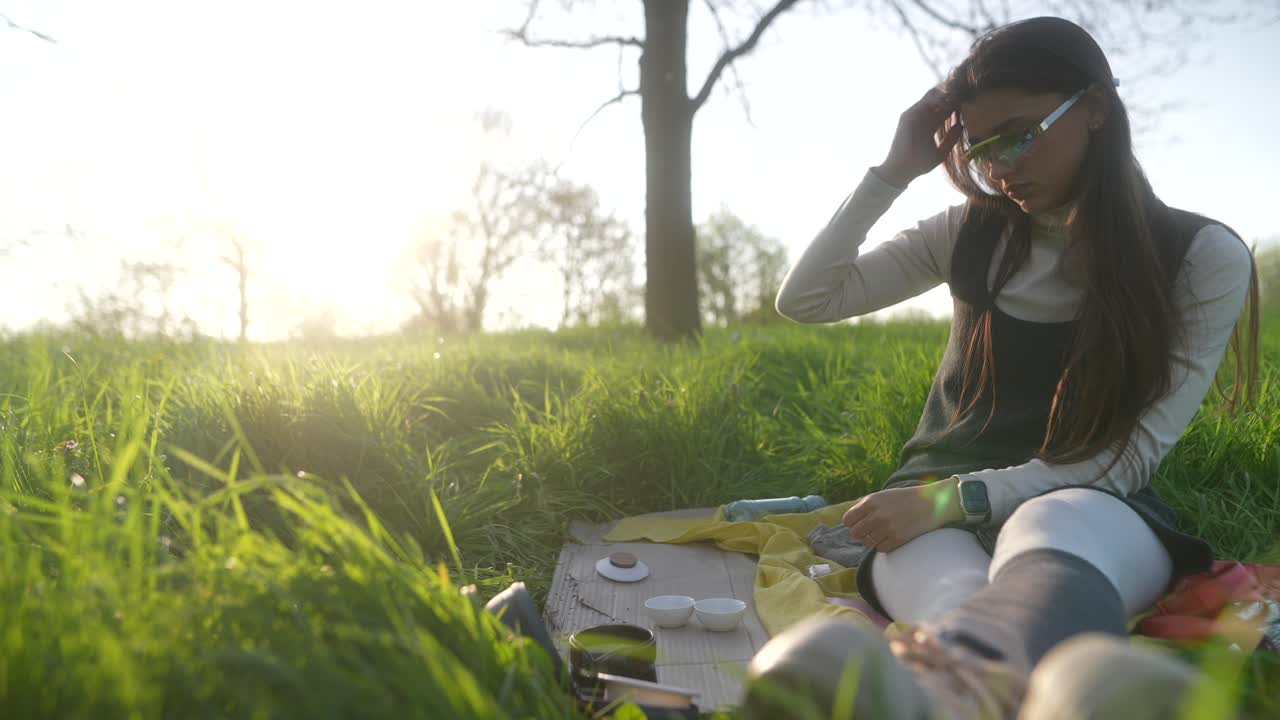 Woman enjoying a tea ceremony in a park at sunset
