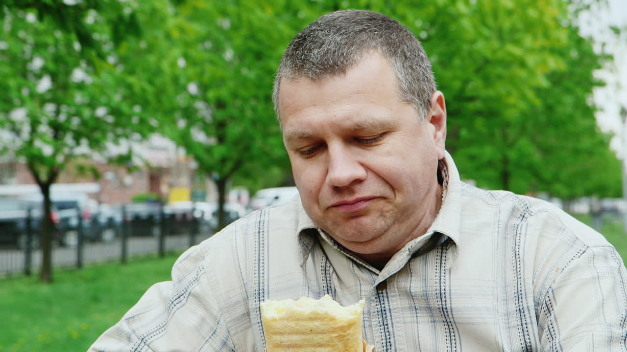 야외에서 패스트푸드를 먹는 잔인한 중년 남성