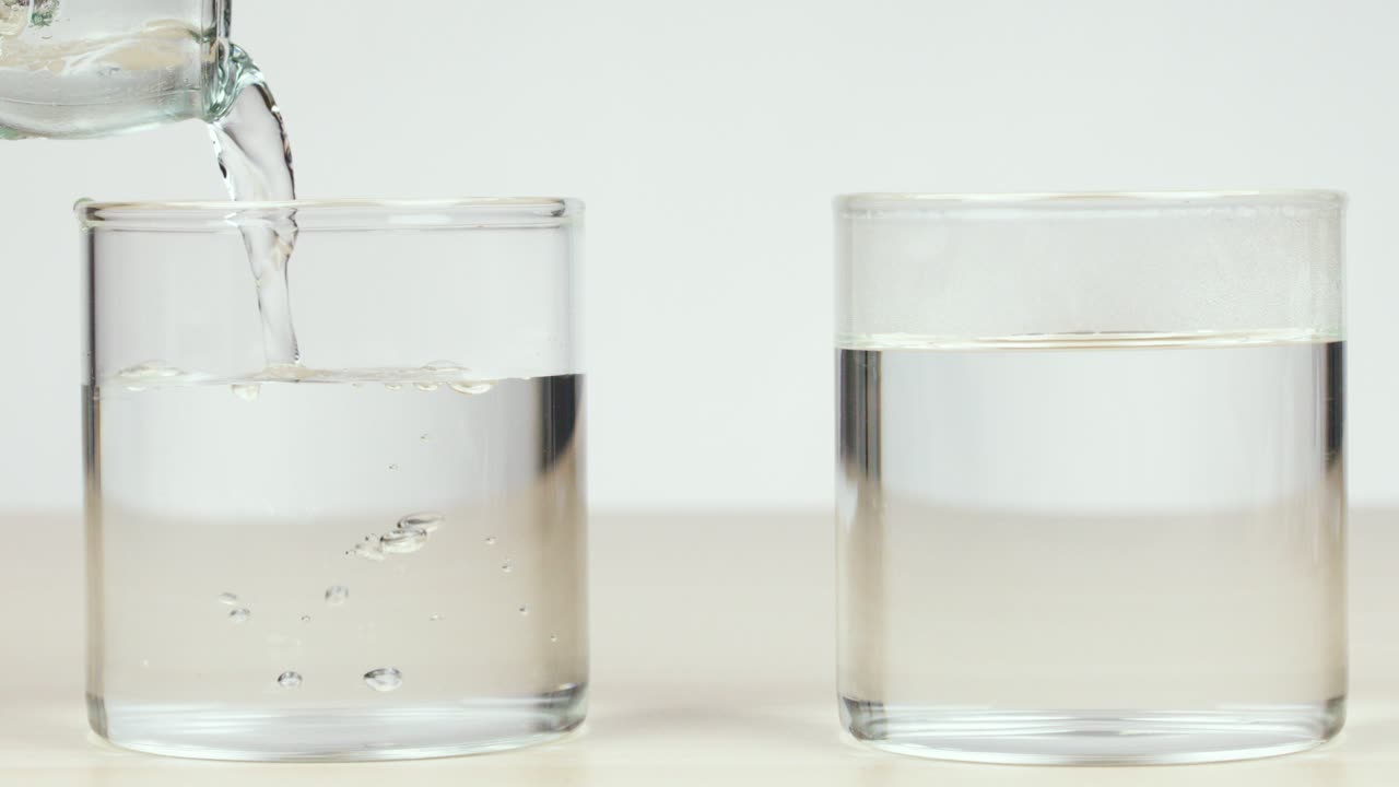 Clear water poured from bottle into glass, neutral background, bright lighting, static camera, scientific context
