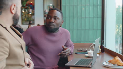 Male-Colleagues-Meeting-in-Cafe-and-Discussing-Project-on-Laptop