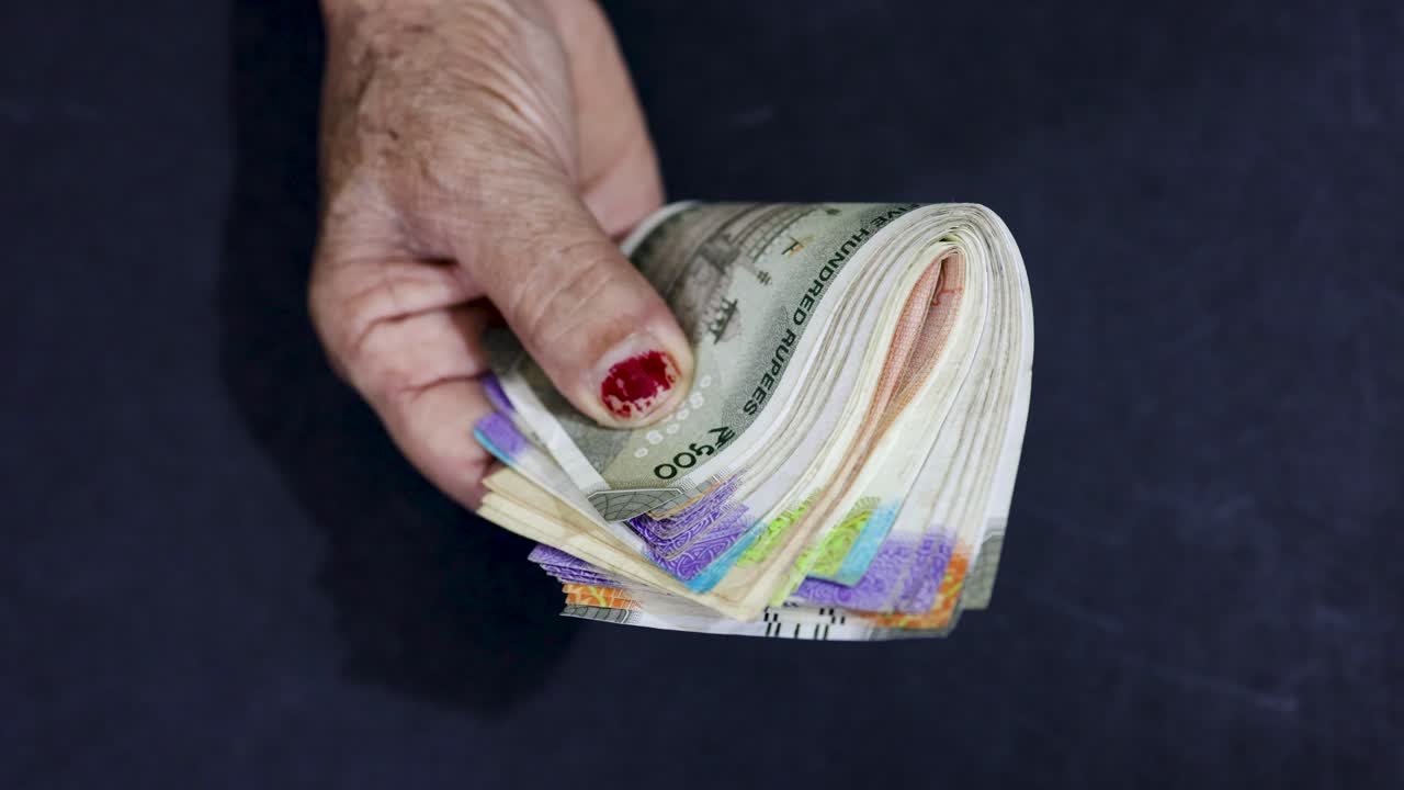 Wrinkled senior hand holding Indian rupee notes symbolizing retirement savings and security
