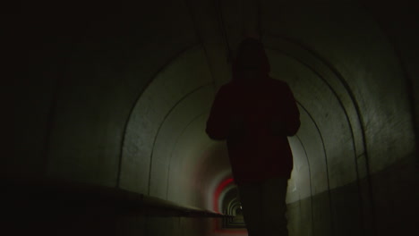 young guy running through tunnel with red light