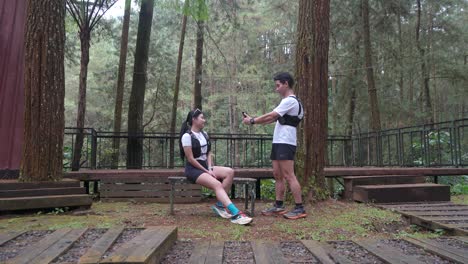 asian couple taking photo with smartphone during outdoor trail run in indonesian forest