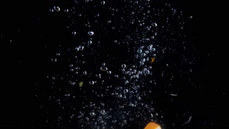Orange-Slices-Falling-into-Water-Super-Slowmotion,-Black-Background,-lots-of-Air-Bubbles,-4k240fps