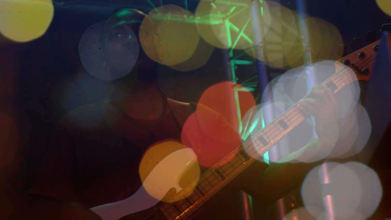 Bassist fretting and plucking on music stage, camera refocusing revealing bass amid shifting bokeh