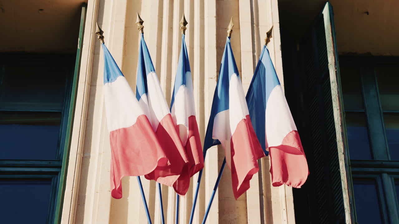 French national flags waving on the facade of a historic building in southern France