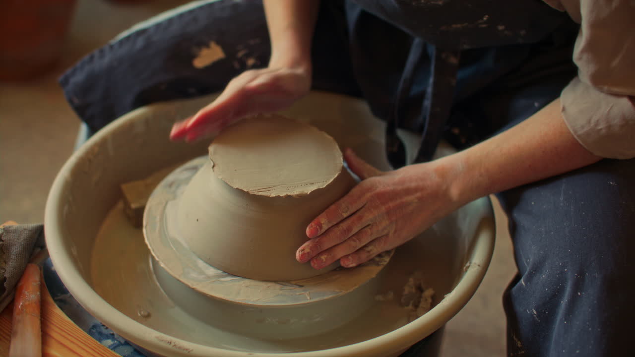 Hands of Ceramist Preparing Clay Bowl for Trimming on Pottery Wheel