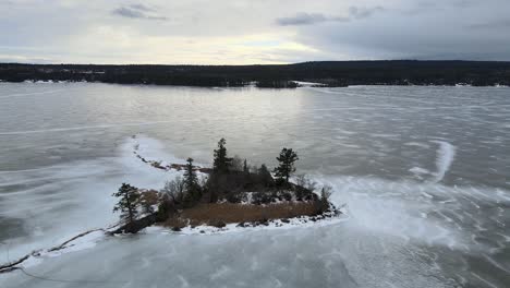 Isolierte-Schönheit:-Eine-Luftaufnahme-Einer-Einsamen-Insel-Inmitten-Eines-Zugefrorenen-Sees-Lac-La-Hache,-Britisch-Kolumbien