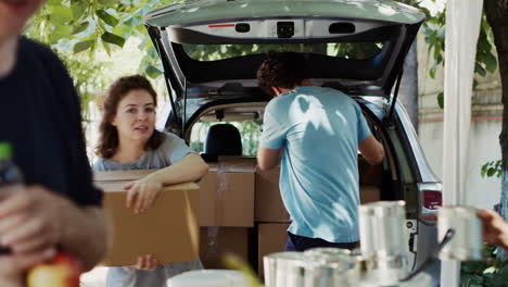 male volunteer giving donations from car