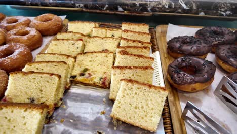 assortment of donuts and sliced cakes at a bakery display