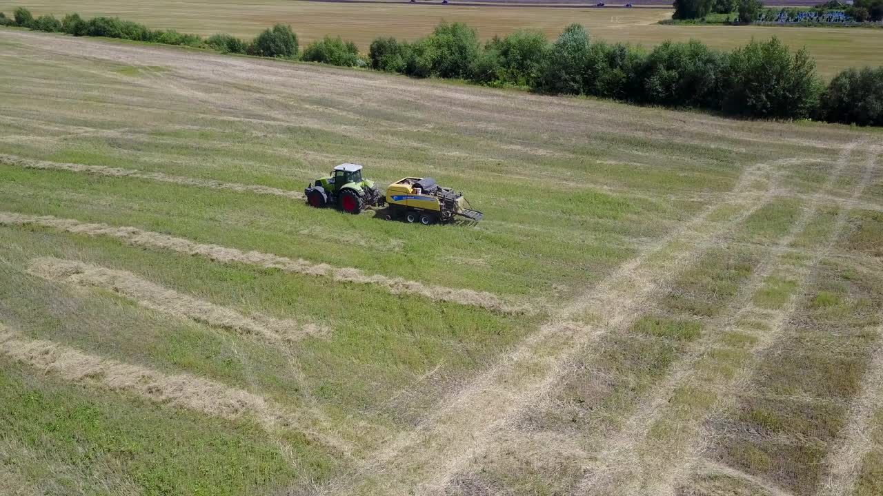 Tractor Collects Hay On The Field. VINNITSA, UKRAINE - JULY 2017: The tractor driver charges loads the collected straw bales