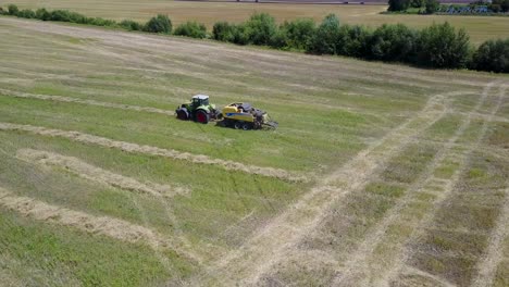 tractor collects hay on the field. vinnitsa, ukraine - july 2017: the tractor driver charges loads the collected straw bales