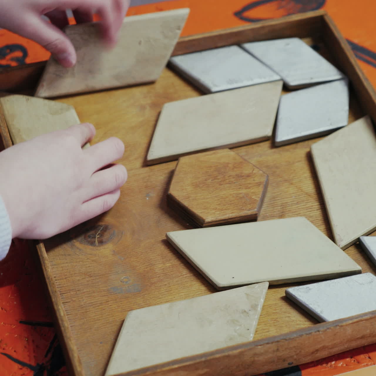 Close up, child's hands compose wooden puzzle of colourful squares on table. Museum of entertaining sciences Square video