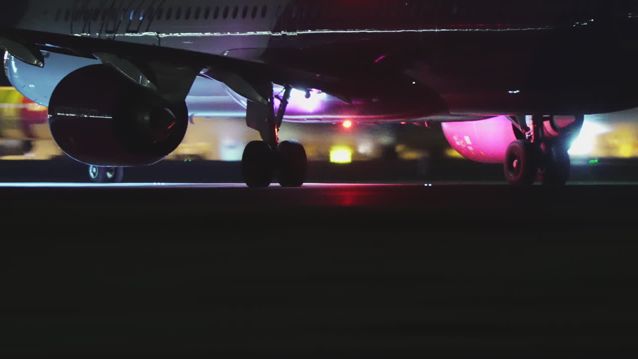 Aereo Wizz Air, primo piano del carrello anteriore e del motore di notte all'aeroporto di Lisbona.