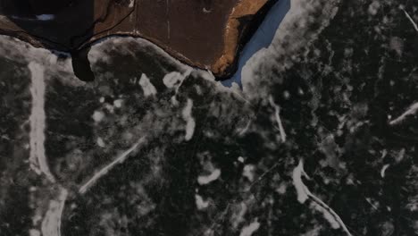top-down aerial of fractured lake ice and volcanic shore near skútustaðir by lake mývatn. reykjahlíð, iceland